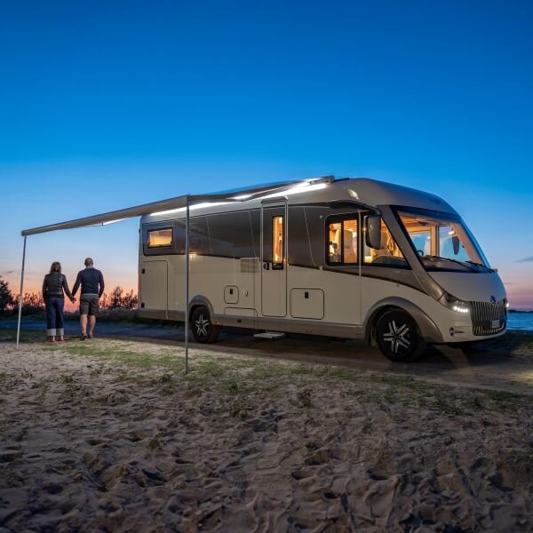 Wohnmobil im Sonnenuntergang mit ausgefahrener Markise, die mit der Markisenbeleuchtung bestückt ist und leuchtet.